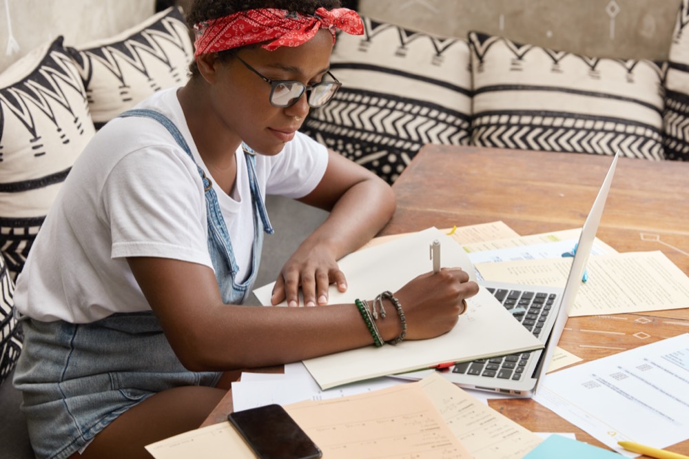 Senior secondary student studying with past papers, notes and a tablet