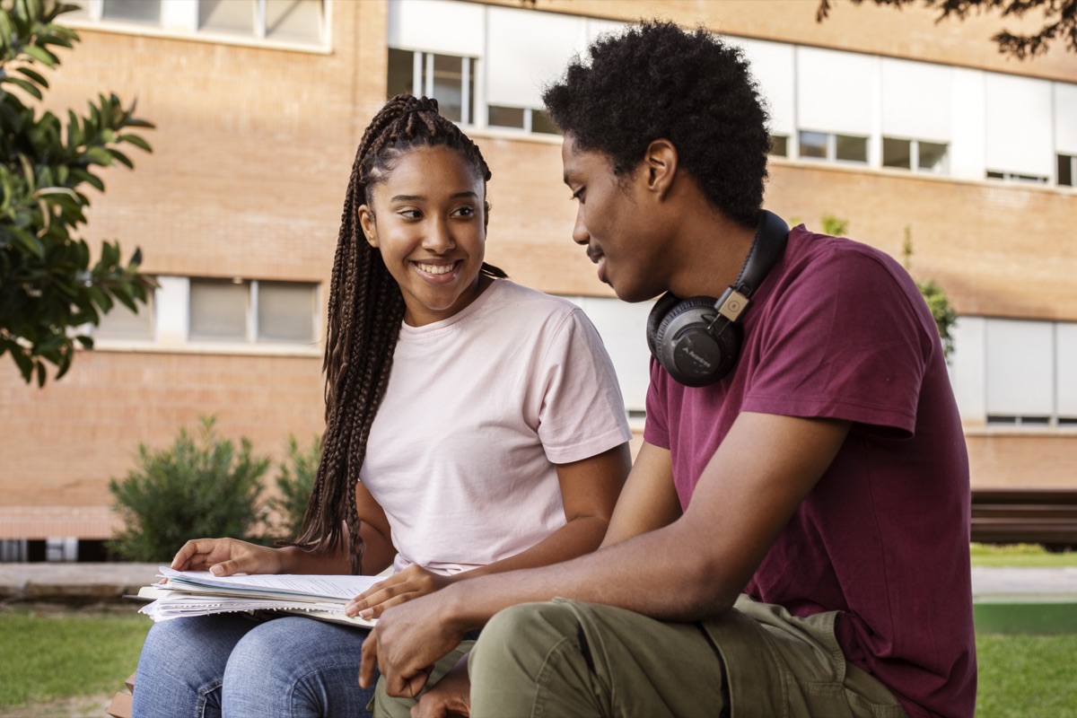 Two students studying together outside their future university campus